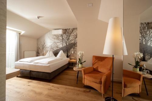 a bedroom with a bed and a chair at Hotel-Restaurant Allmer in Weiz