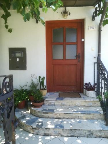 una porta rossa su una casa bianca con piante in vaso di Apartma Zalka a Izola