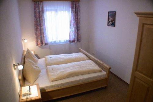 a small bedroom with a bed with a window at Haus Koller in Kaprun
