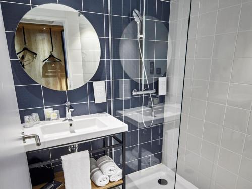 ボルドーにあるRadisson Hôtel Bordeaux Saint-Jeanの洗面台、鏡、シャワー付きのバスルーム