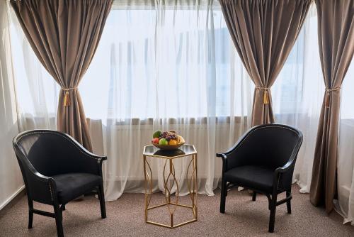 two chairs and a table with a bowl of fruit in front of a window at Riviera by Queens Hotel and Resort in Gura Văii
