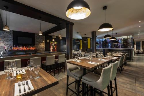 a restaurant with tables and chairs and a bar at Imperia Hôtel et Suites Terrebonne in Terrebonne