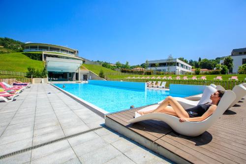 Un uomo sdraiato su una poltrona accanto a una piscina di Las Caldas by blau hotels a Las Caldas