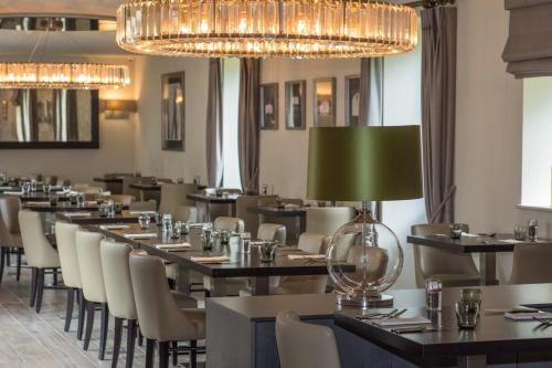 a restaurant with tables and chairs and a green lamp at Dunalastair Hotel Suites in Kinloch Rannoch