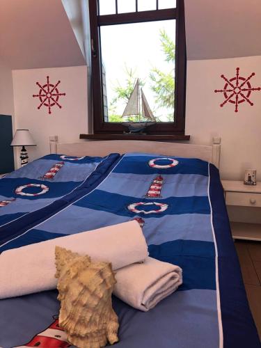 a bedroom with a blue bed with towels and a window at Villa Papaj in Międzyzdroje