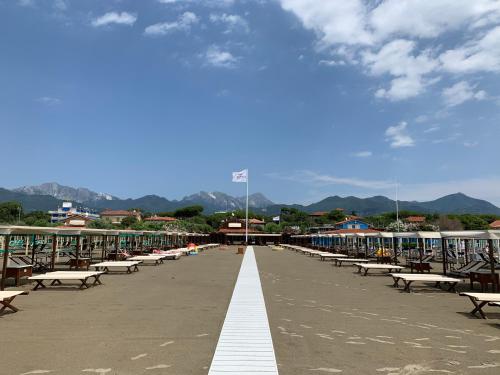 a row of benches on a beach with mountains in the background at Exclusive Loft 300mt by the sea Forte dei Marmi in Forte dei Marmi