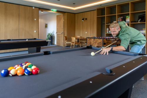a man playing pool with a cue on a pool table at eduCARE Hotel in Treffen