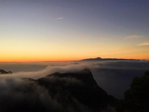 a view of the sun setting over the clouds on a mountain at B&B and Apartments El Charco Azul in El Risco