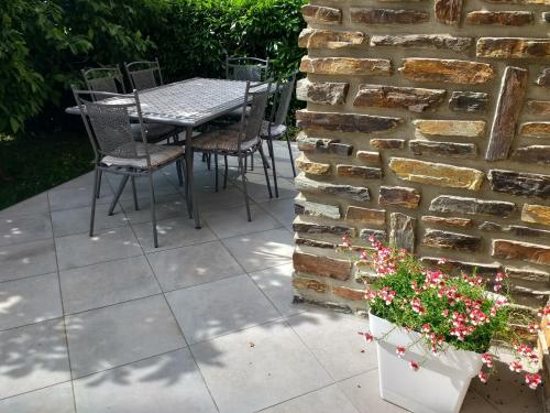 a patio with a table and chairs against a brick wall at Les Ecureuils in Revin