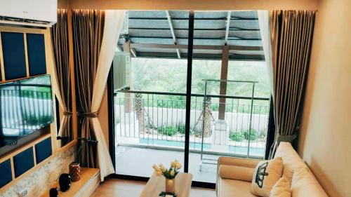 sala de estar con sofá y ventana grande en Pleasant Chiangmai en Chiang Mai