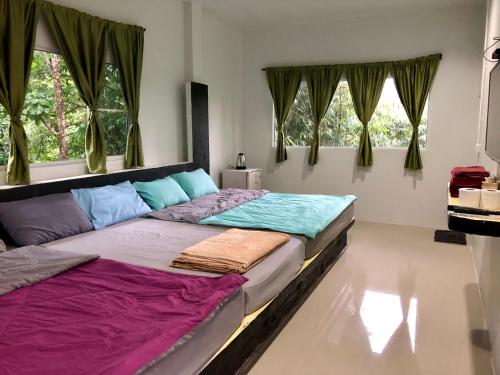 two beds sitting in a room with windows at chillchillsangkhlaburi โรงแรมชิลชิลสังขละบุรี in Sangkhla Buri