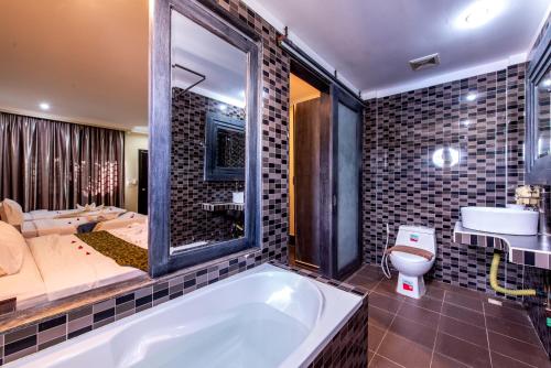 a bathroom with a bath tub and a bedroom at Central Night Hotel in Siem Reap