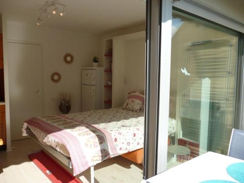 a bedroom with a bed and a sliding glass door at Studio LUMINEUX avec belle TERRASSE sur ESPACES VERTS, 100m PLAGE in Carnac-Plage