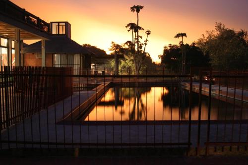a swimming pool with a sunset in the background at Chaminuka Lodge in Lusaka