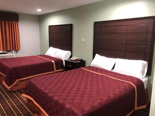 a hotel room with two beds with red covers at Texas Inn and Suites Lufkin in Lufkin