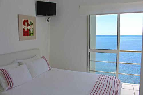 a bedroom with a white bed and a large window at The Artist Villa in Santa Cruz