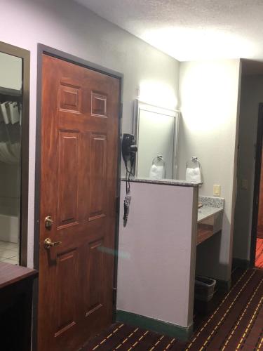 a bathroom with a wooden door and a mirror at Texas Inn and Suites Lufkin in Lufkin