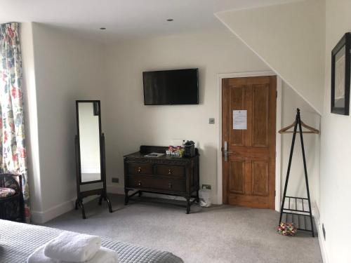 um quarto com uma cama, uma cómoda e uma televisão em Avenue House em Bakewell