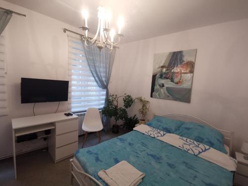 Schlafzimmer mit einem Bett, einem Schreibtisch und einem TV in der Unterkunft Apartament wygodny S3 in Kalisz