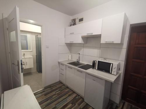 a white kitchen with a sink and a microwave at Apartament wygodny S3 in Kalisz