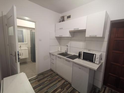 eine weiße Küche mit einer Spüle und einer Mikrowelle in der Unterkunft Apartament wygodny S3 in Kalisz