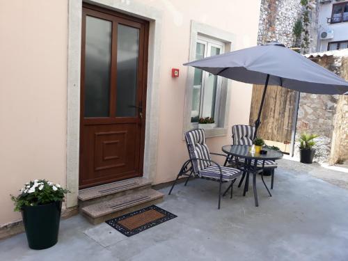 a patio with a table and chairs and an umbrella at App Paris 5 in Umag