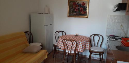 a kitchen with a table with chairs and a white refrigerator at Apartment Perović in Baška Voda
