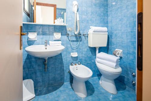 bagno piastrellato blu con servizi igienici e lavandino di Hotel Astor a Lido di Jesolo