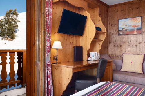 a room with a wooden wall with a desk and a bed at Hôtel Les Balcons Village in Belle Plagne
