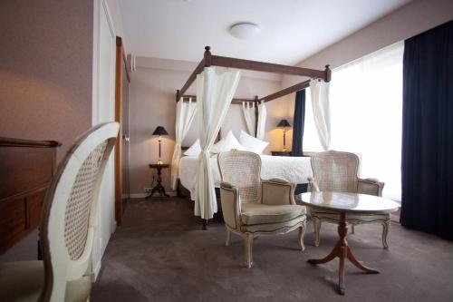 Schlafzimmer mit einem Bett, einem Tisch und Stühlen in der Unterkunft Hotel De Hofkamers in Ostende