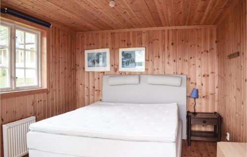 - une chambre avec un lit blanc dans un mur en bois dans l'établissement Cozy Home In Ljungby With Kitchen, à Ljungby