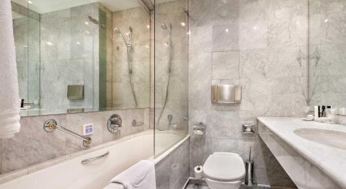 a bathroom with a tub and a toilet and a sink at Dvorak Spa & Wellness in Karlovy Vary