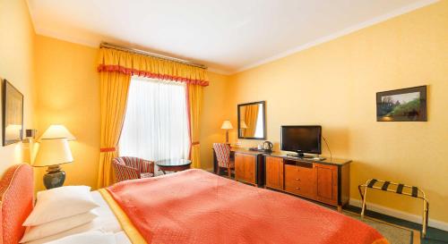 a hotel room with a bed and a television at Dvorak Spa & Wellness in Karlovy Vary