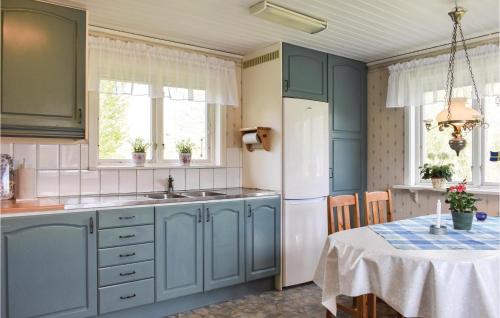a kitchen with blue cabinets and a table with a table cloth at Pet Friendly Home In Listerby in Listerby