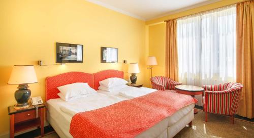 a hotel room with a bed and two chairs at Dvorak Spa & Wellness in Karlovy Vary