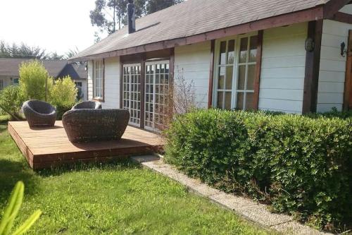 a house with a wooden deck with two chairs on it at Casa Tunquen VIP in Tunquen