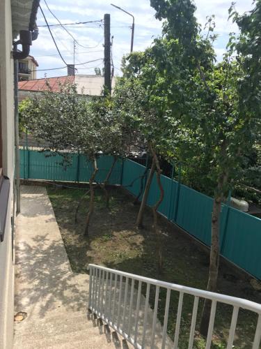 a fence with trees in front of a house at Wooden Museum in Kutaisi