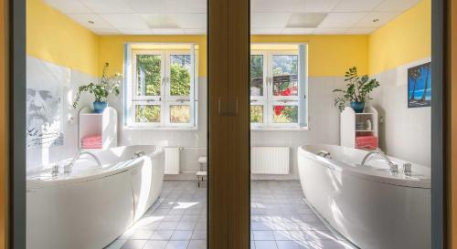 a bathroom with two tubs and two windows at Dvorak Spa & Wellness in Karlovy Vary