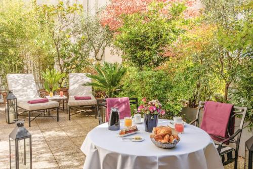 una mesa blanca con una cesta de comida en el patio en L'Hôtel, en París