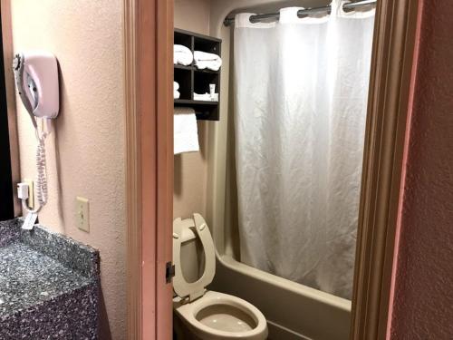 a bathroom with a toilet and a shower and a phone at Legacy Inn - Gallatin in Gallatin