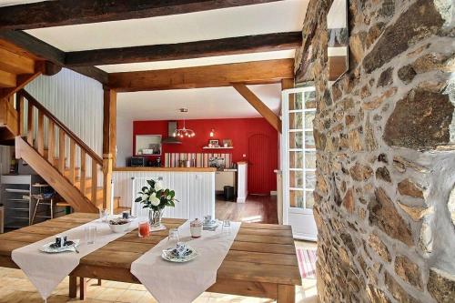 a dining room with a table and a stone wall at Holiday home Le Gite de Kerneuil in Gommenecʼh