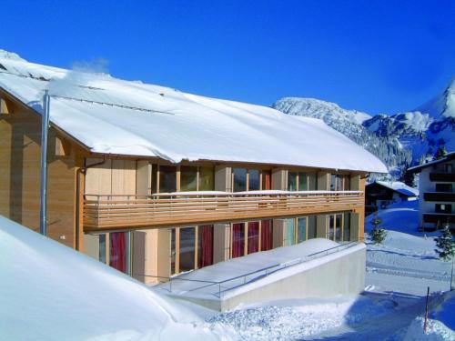 una casa cubierta de nieve con techo cubierto de nieve en Caroline´s Appartement in Warth am Arlberg, en Warth am Arlberg