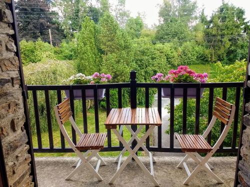 two chairs and a table on a balcony with flowers at Les Ecureuils in Revin