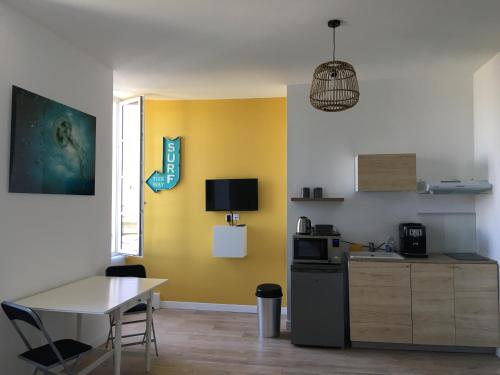 une cuisine avec une table et un mur jaune dans l'établissement Le Beach centre la Brèche wifi vue jardin, à Niort