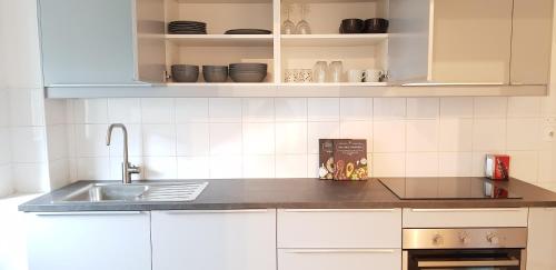 Una cocina con gabinetes blancos y un fregadero. en Le Bas Rebberg - Face Gare, en Mulhouse