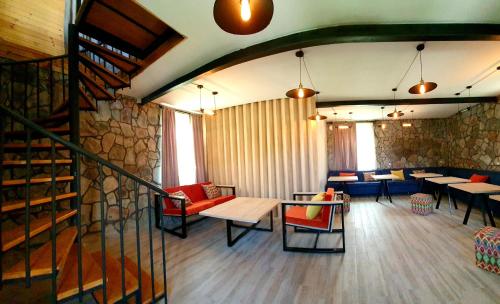 a restaurant with tables and chairs and a stone wall at Hotel Migu Yard in Stepantsminda