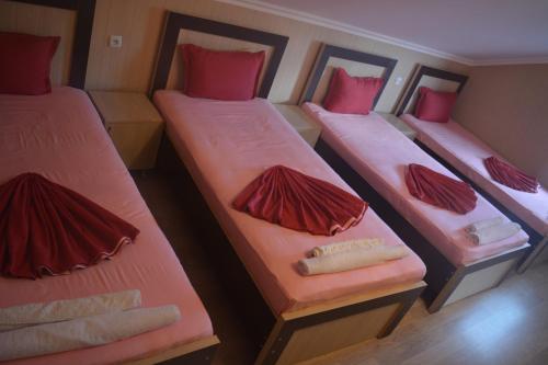 three beds in a small room with red pillows at Millennium Rabati in Akhaltsikhe