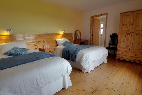 1 dormitorio con 2 camas y pared de madera en Behan's Lodge, en Doonbeg