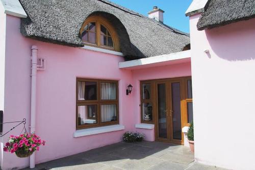 una casa rosa con techo negro en Behan's Lodge en Doonbeg