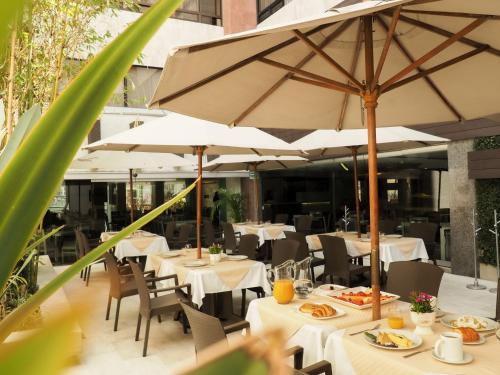 a restaurant with white tables and umbrellas at Hotel Marbella in Mexico City